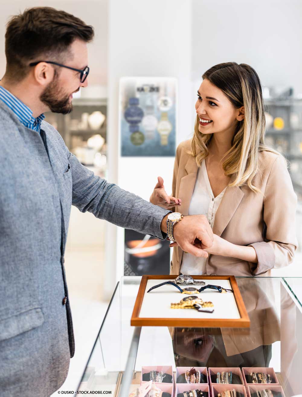 Schmuckerkäuferin berät einen Kunden beim Uhrenkauf